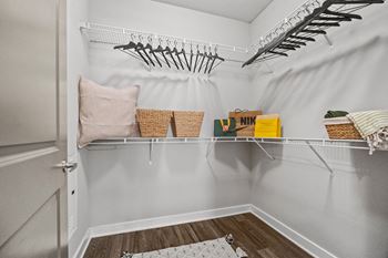 A white closet with a basket and a yellow box on the shelf.